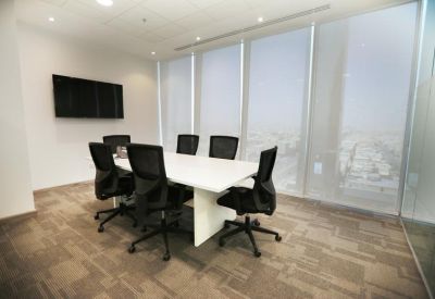 Modern meeting room with a white conference table, black seating, and a wall-mounted TV screen.