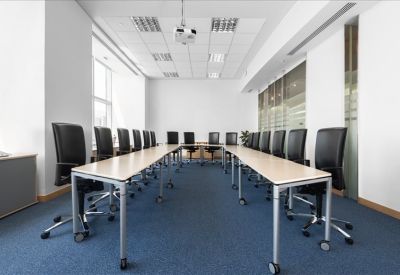 Large U-shaped meeting room with black chairs and a ceiling projector.
