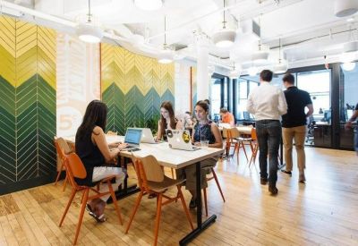 Modern coworking area with long tables and a vibrant green and yellow chevron feature wall.
