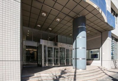 Building entrance of Kinko Building with glass sliding doors and a large grey pillar.
