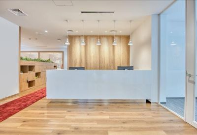 Bright reception area with a minimalist white desk, wooden floors, and hanging pendant lights.