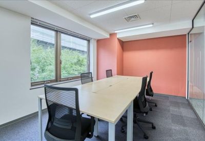 Private office suite with a wooden table, ergonomic chairs, and a pink feature wall.