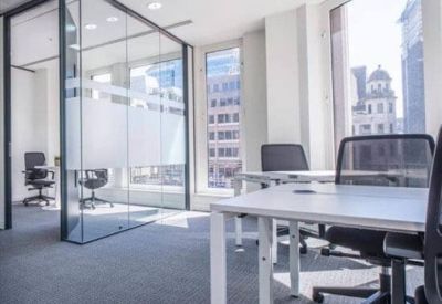 Bright corner workspace featuring glass partitions and large windows with urban views.