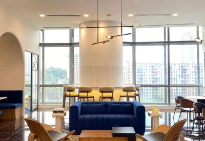 Bright communal lounge with a blue velvet sofa and modern pendant lighting.