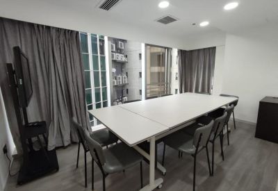 Meeting room at Kyoto Plaza with a long white table, grey chairs, and a large monitor on a stand.