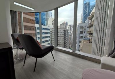 Modern lounge area with stylish dark armchairs positioned by a curved window overlooking the city.