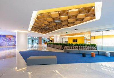 Modern reception lounge with a geometric wooden ceiling feature and blue carpeted area.