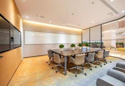 Professional meeting room with a large wooden table, potted plants, and glass walls.