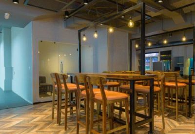 Stylish high-top communal dining area with wooden stools and warm industrial lighting.