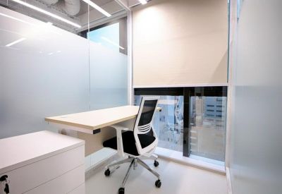 Private office suite with a white desk, ergonomic chair, and frosted glass partitions.