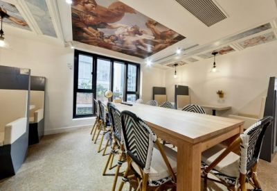 Communal dining area featuring a renaissance-style ceiling mural and large wooden table.