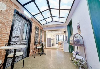 Bistro-style corridor with brick walls, cafe seating, and a glass-paneled ceiling.