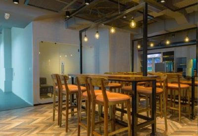Coworking area with high wooden tables, bar stools, and warm industrial pendant lighting.