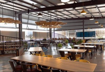 Spacious communal dining area with long wooden tables and industrial pendant lighting.