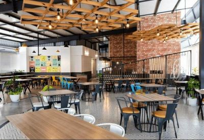Bright breakout space with brick walls, indoor plants, and a wooden lattice ceiling.