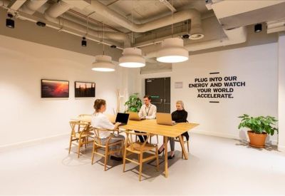 Bright meeting room with a wooden table, four people, and motivational wall text.