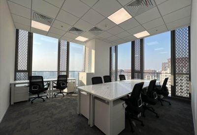 Bright private office with two separate desks and large windows showing city views.