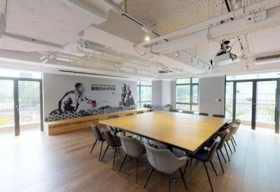 Large meeting room with a square wooden table, grey chairs, and a sports-themed wall mural.