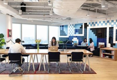 Coworking space featuring long wooden desks and a blue geometric accent wall.