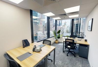Private corner office with two desks and large windows overlooking the city.