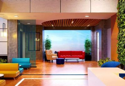 Bright breakout space with a red leather sofa and large windows providing natural light.