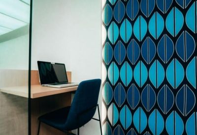Private work pod featuring a desk, laptop, and a vibrant blue leaf-patterned acoustic wall.