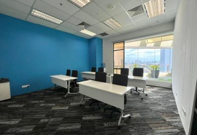 Bright training room with blue feature wall and multiple white desks.