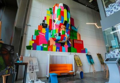 Bright creative lounge featuring a large colorful geometric wall mural and artist easels.
