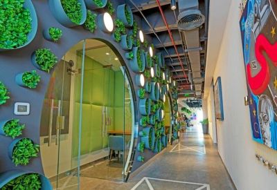 Modern corridor featuring circular glass office pods and a vibrant vertical garden wall.