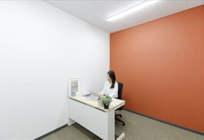 Private office suite with a white desk and a vibrant orange accent wall.