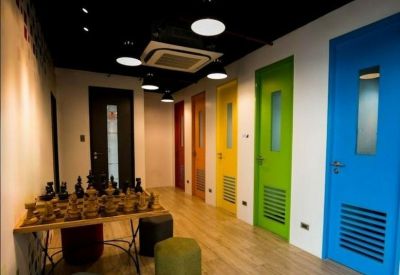 Modern hallway featuring a row of vibrant, colorful doors and a large chess set on a wooden table.