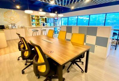 Bright coworking area with a wooden table, yellow chairs, and blue geometric wall panels.