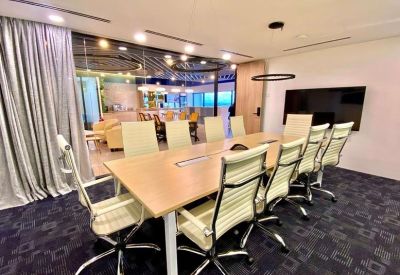 Executive boardroom featuring a long wooden table and cream leather chairs.