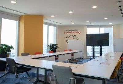 Spacious u-shaped meeting room with yellow accent wall and natural light.