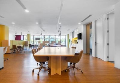 Large open-plan lounge with wooden floors and a central light-wood collaborative table.