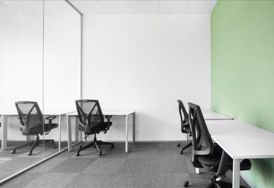 Bright coworking area with workstations against white and soft green walls.