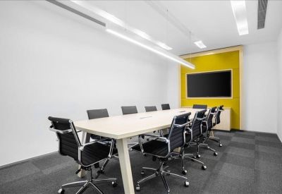 Professional boardroom with a long white table and a yellow feature wall with a monitor.