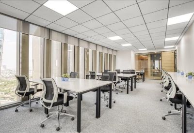 Bright, open-plan office space with white desks and black mesh chairs near large windows.