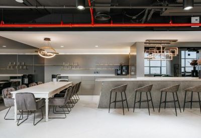 Bright breakout kitchen with a long white dining table and a sleek grey marble breakfast bar.