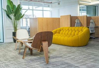Open-plan office space featuring a vibrant yellow sofa and ergonomic workstations.