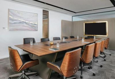 Professional boardroom with a large wooden table, leather chairs, and wall-mounted screen.