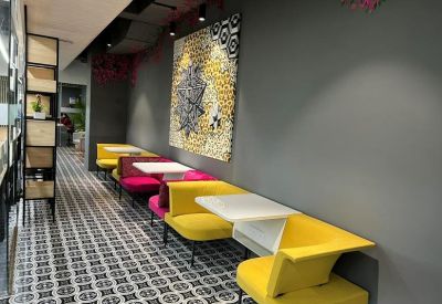 Communal breakout area with vibrant yellow and pink booth seating.