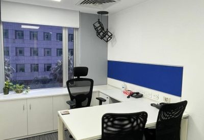 Modern L-shaped desk in a private office with blue accents and city views.