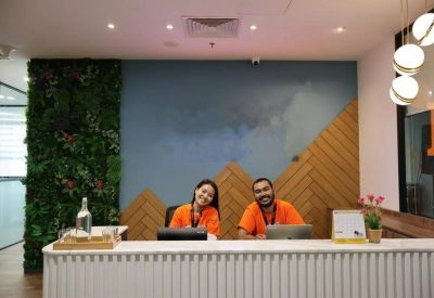 Bright reception desk with a lush vertical green wall and geometric wood paneling.