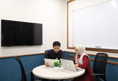 Small meeting room featuring a round white table, blue walls, and a large whiteboard.