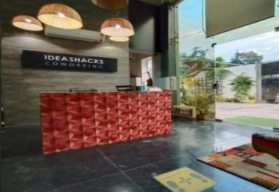Modern reception area of Ideashacks Coworking featuring a red textured desk and wicker pendant lights.