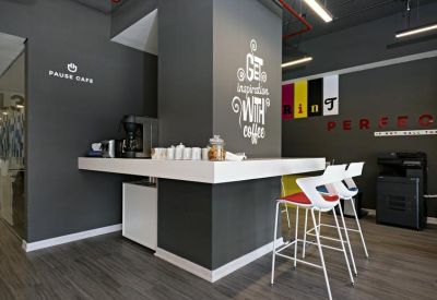 Modern café area with a dark grey feature wall and white high-top seating.