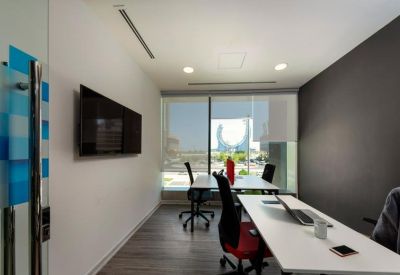Bright workspace with white desks, black office chairs, and views of the city skyline.