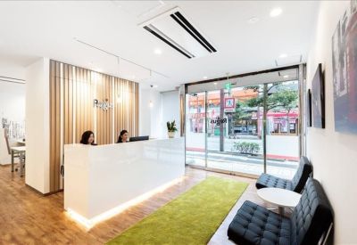 Bright reception area with a sleek white front desk and lime green rug.