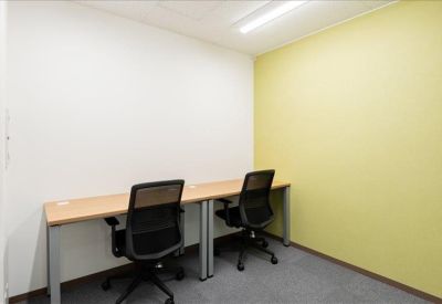 Bright two-person office suite with light wood desks and a lime green feature wall.